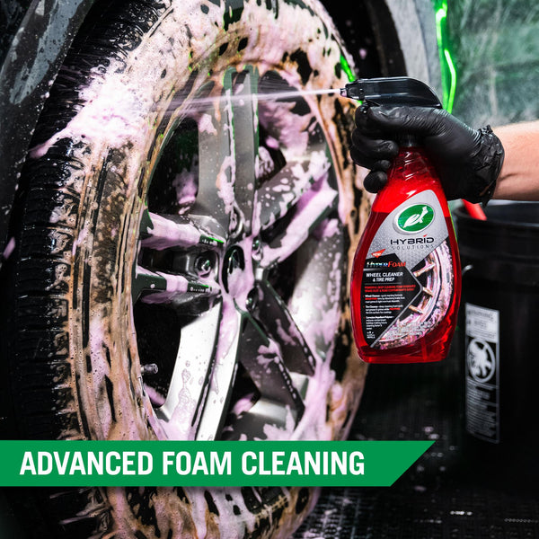 A hand is spraying the red thick foam of Hyper Foam Wheel Cleaner onto the wheel of a car. 