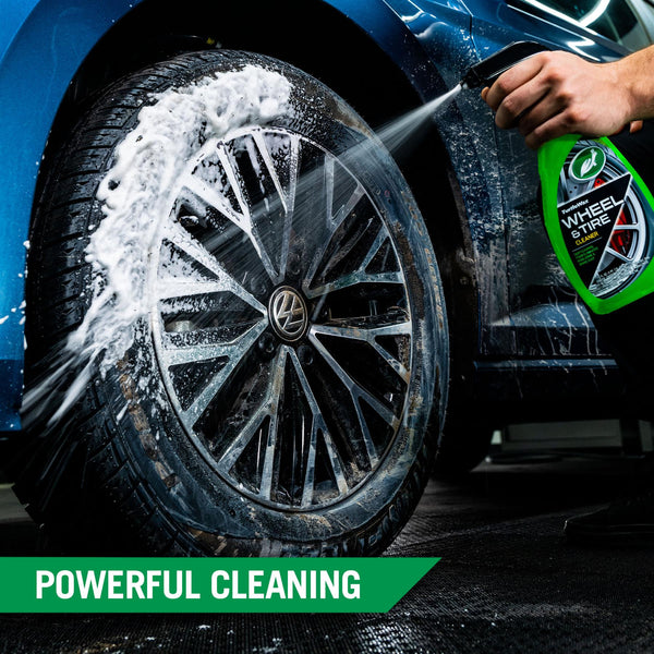 Detailed shot of thick foam from Turtle Wax Wheel & Tire cleaner being sprayed onto the tire of a blue Volkswagen. It highlights the powerful cleaning & foaming formula.