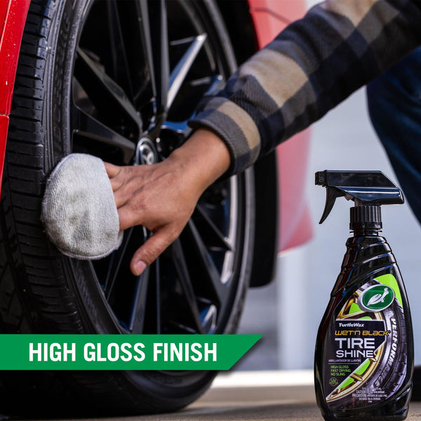 A hand uses a grey applicator pad to wipe Wet'n Black Tire Shine to the tire of a car, highlighting the high gloss finish of the product. 